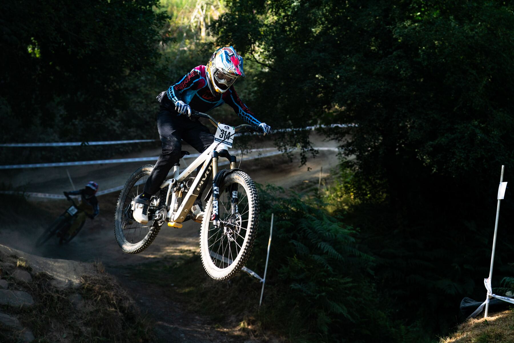 Stanlie Britt catching air through a wooded downhill section